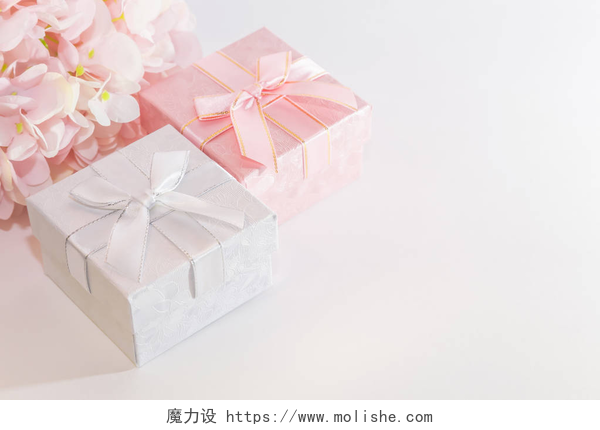 带有粉红色和银色的礼品盒带有粉红色和银色礼品盒的贺卡的节日背景，带有蝴蝶结和人工绣球花，白色背景上柔和的颜色，带有复制空间